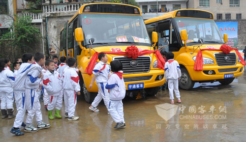 孩子们兴奋地围绕着宇通大鼻子校车