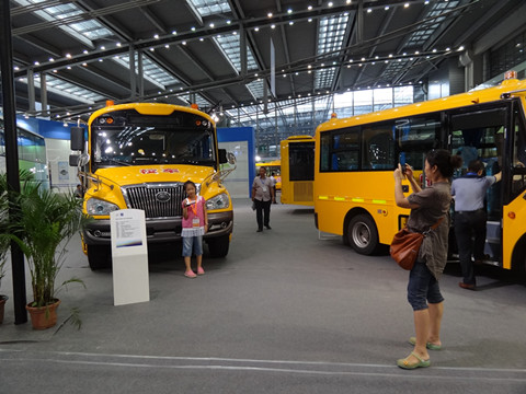 展会现场，一位小朋友和宇通大鼻子校车合影