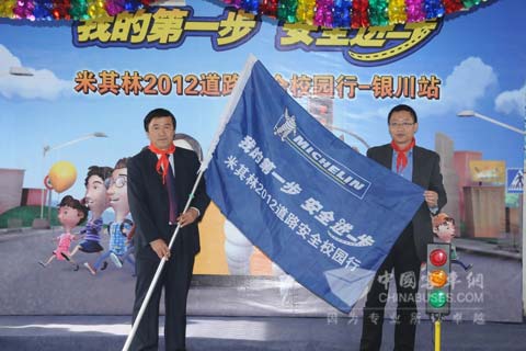 米其林（中国）品牌与传播部总监张震先生向银川泾龙回民小学曹华校长授予旗帜